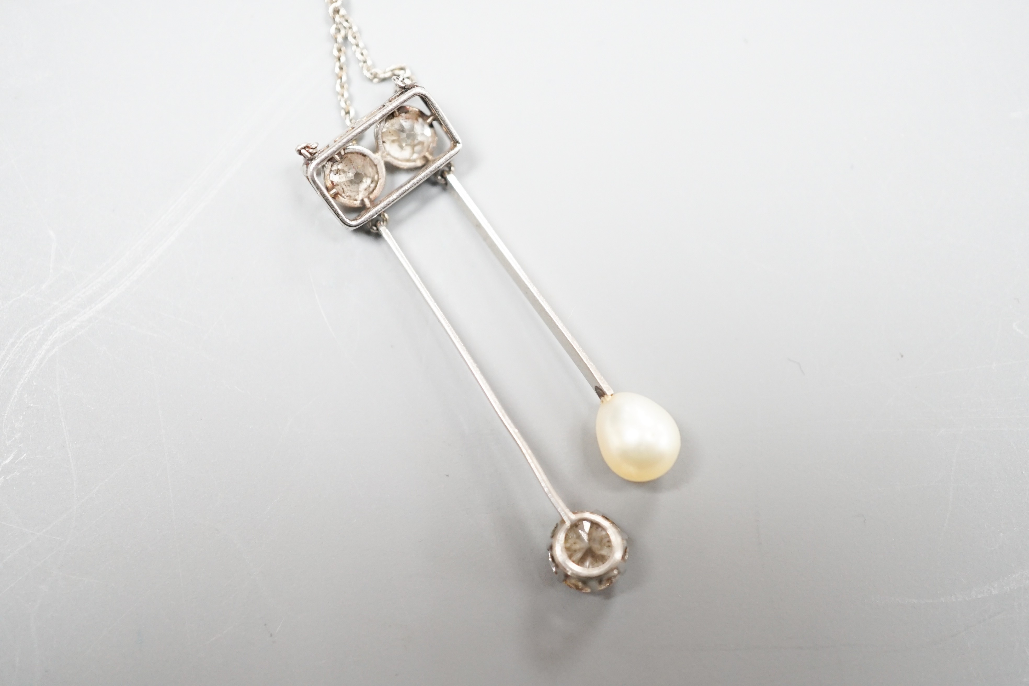 A 1940's white metal (probably platinum), three stone diamond and single stone teardrop shaped pearl set double drop pendant necklace, pendant 39mm, chain 41cm, gross weight 5.9 grams.